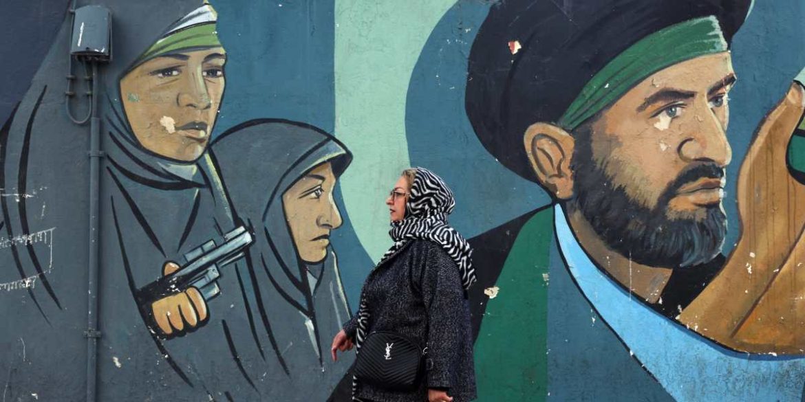 Una donna iraniana cammina accanto a un dipinto murale raffigurante soldati iraniani a Teheran Una donna iraniana cammina accanto a un dipinto murale raffigurante soldati iraniani a Teheran
