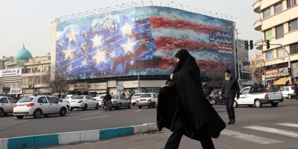 Una donna iraniana cammina davanti a un grande cartellone pubblicitario anti-USA in piazza Enqelab Una donna iraniana cammina davanti a un grande cartellone pubblicitario anti-USA in piazza Enqelab