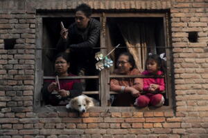 Una famiglia osserva dal balcone della propria casa il passaggio della manifestazione religiosa dedicata alla divinità Naradevi