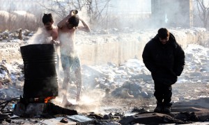 Due ragazzi si lavano usando l’acqua di un barile 