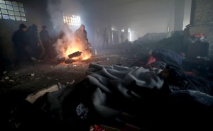 Alcuni profughi riposano riscaldati dalle fiamme del fuoco