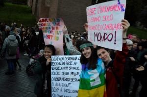 13 - Tre ragazze mostrano orgogliosamente i loro ideali sui cartelli. Fra questi 'Scusate l'inconveniente, stiamo solo cercando di cambiare il mondo'.