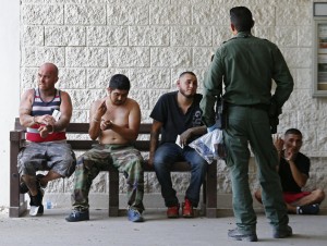 Un agente sorveglia le persone fermate perché sospettate di voler entrare illegalmente negli Usa, vicino McAllen. 