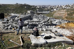 La famiglia palestinese seduta sui resti della propria casa, osserva i pochi averi rimasti dopo la demolizione. 