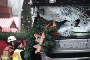 Un vigile del fuoco e un poliziotto ispezionano il camion danneggiato dalla corsa