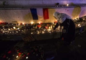Una donna illuminata dalle candele in Place de la Republique a un anno dagli attentati terroristici