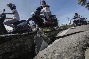 foto 2 motociclisti attraversano una strada lesionata dal sisma